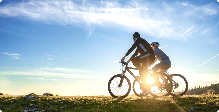 Važiuojantys dviratininkai saulėtekio metu