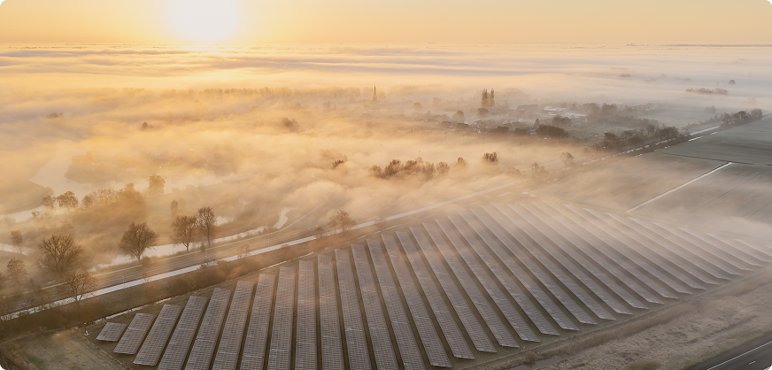Saulės elektrinių parkas matomas iš paukščio skrydžio, ankstų rytą, šviečiant saulei ir aplink telkšant rūkui.