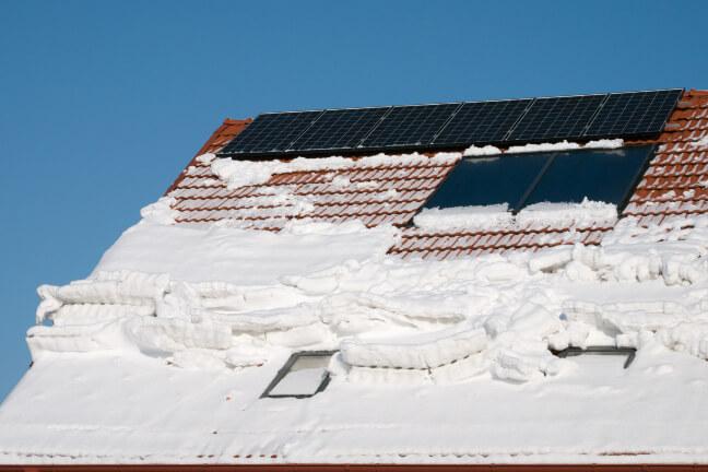 Apsnigta saulės elektrinė ant namo stogo