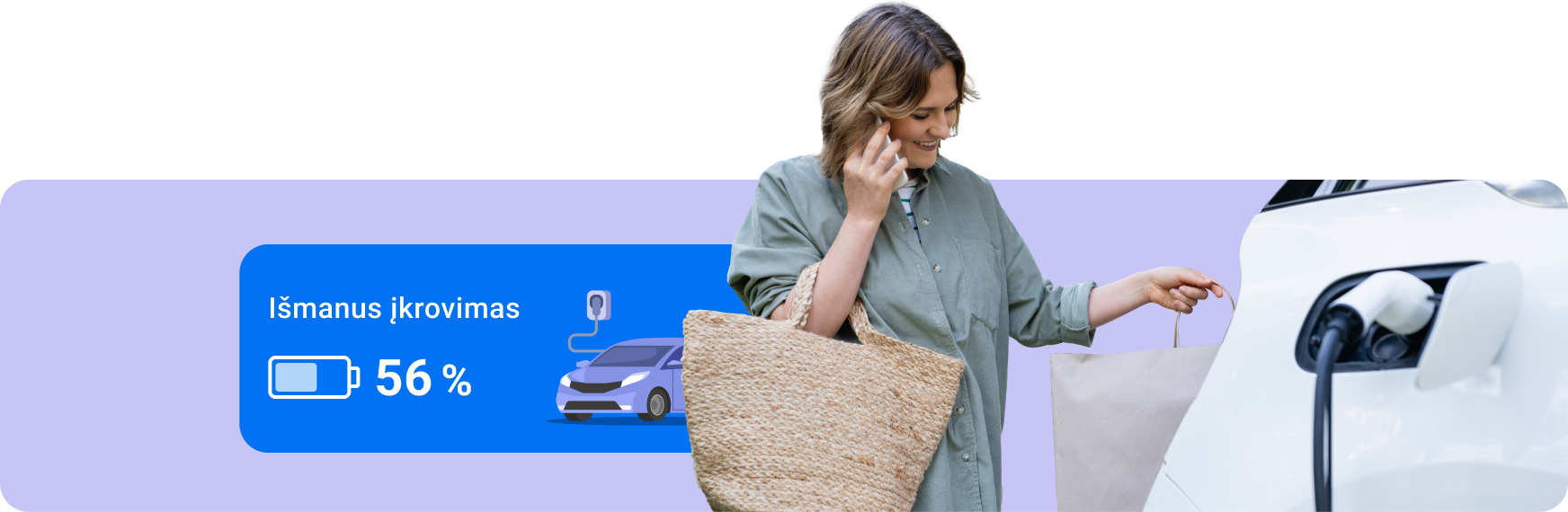 Moteris su pirkinių krepšiais kalba mobiliu telefonu ir tuo pat metu naudojasi išmaniu elektromobilio įkrovimu.
