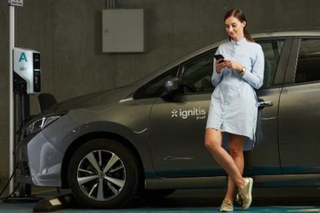 Mergina šalia elektromobilio