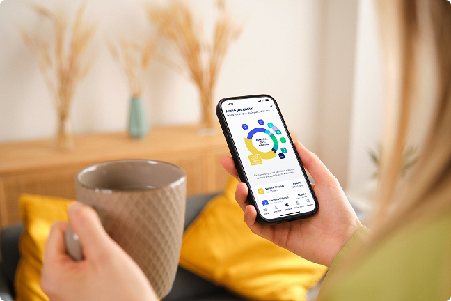 Moteris rankose laiko kavos puodelį ir telefoną su atidaryta EnergySmart programėle
