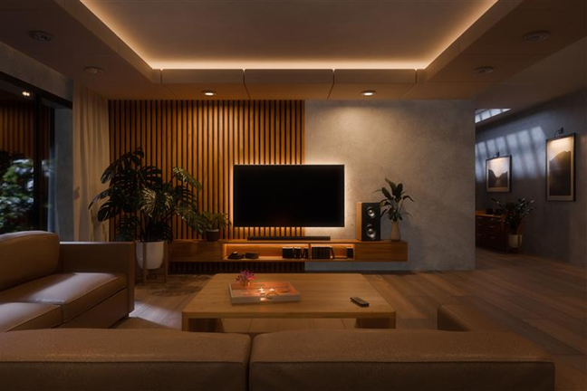 Jaukiai apšviesta svetainė vakare, jos centre - televizorius.