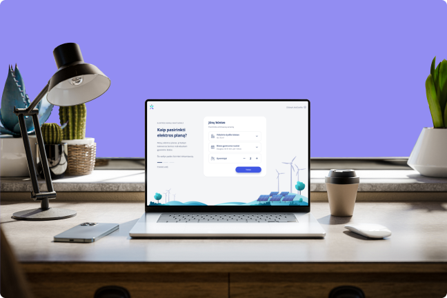 Ant stalo padėtas nešiojamas kompiuteris, kurio ekrane matosi atnaujinta elektros kainų skaičiuoklė.